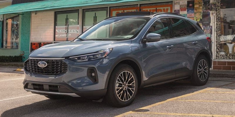 Dark gray Ford Escape SUV parked in a lot, with a storefront building in the background
